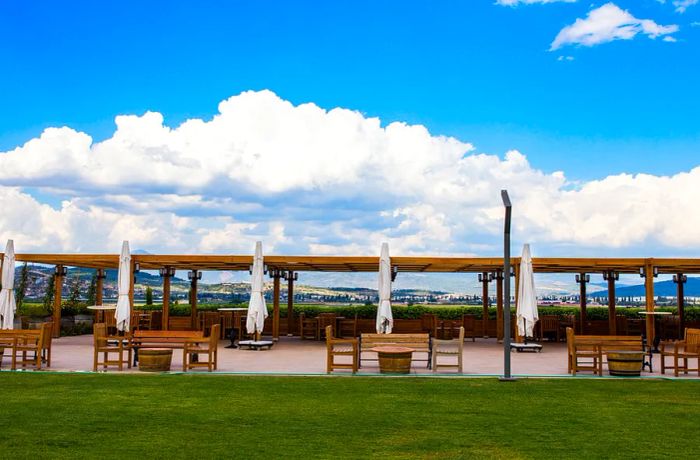 Patio tables shaded by an awning under a breathtaking blue sky adorned with clouds.