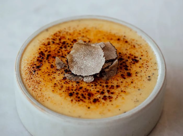 A crème brûlée elegantly garnished with shaved truffles.