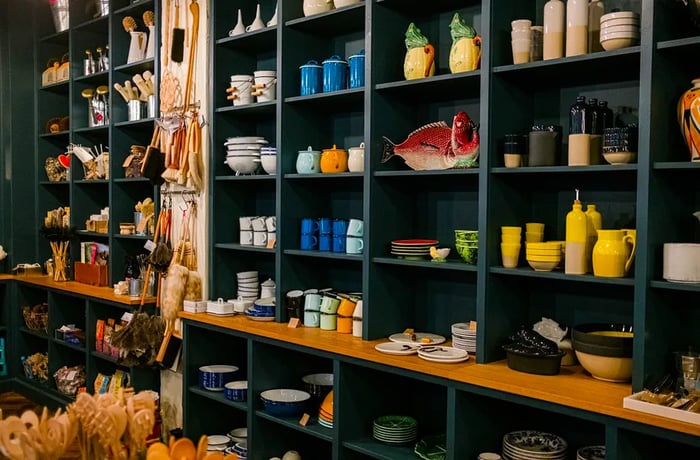 Shelves in a deep green hue, stocked with an array of kitchenware.