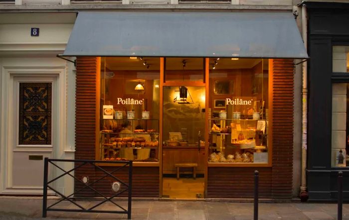 A warmly illuminated bakery storefront at dusk.