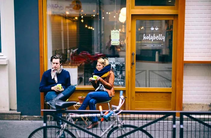 Two patrons relax at a café with snacks.