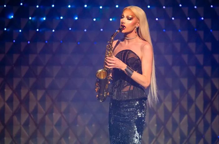 A drag performer showcases their saxophone skills on stage.