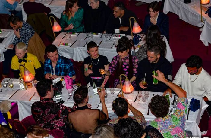 Patrons raise their glasses in a toast around a lengthy table.