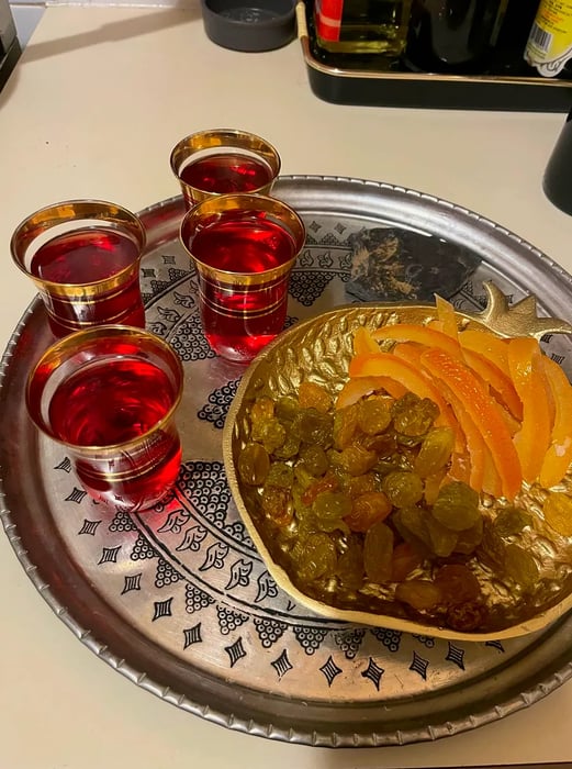 Crimson tea cups accompanied by raisins and candied orange peel.