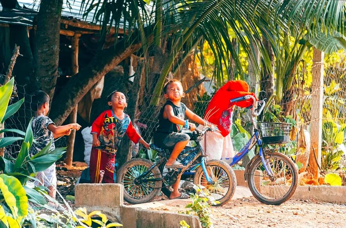 Kids on bikes pull silly faces for the camera in Vang Vieng, Laos.