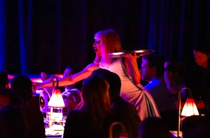 A server delivers an order in a bustling, dimly lit bar.