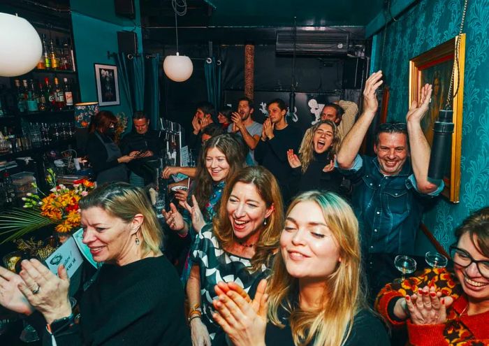 Bar patrons enthusiastically cheer for an unseen performer.