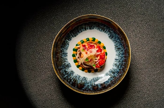 A vibrant lobster dish is presented from above against a dark backdrop.