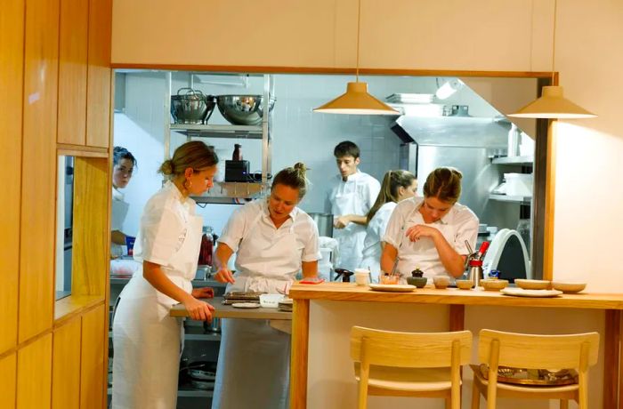 Chefs diligently working in a bright, light-wood open kitchen.