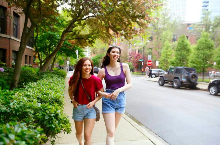 Two young women stroll arm-in-arm, sharing laughter on a Chicago street