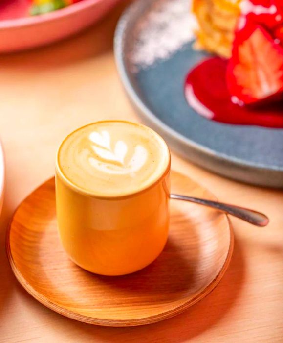 A petite latte, placed alongside a spread of brunch dishes.