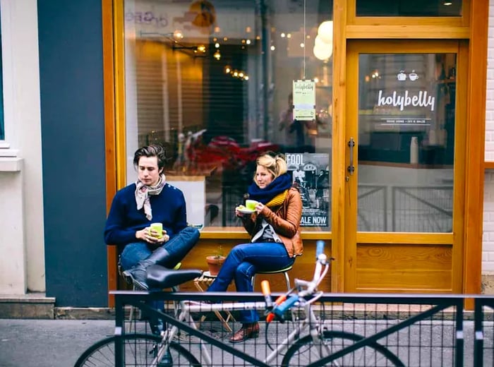 Two patrons enjoy snacks outside a café.