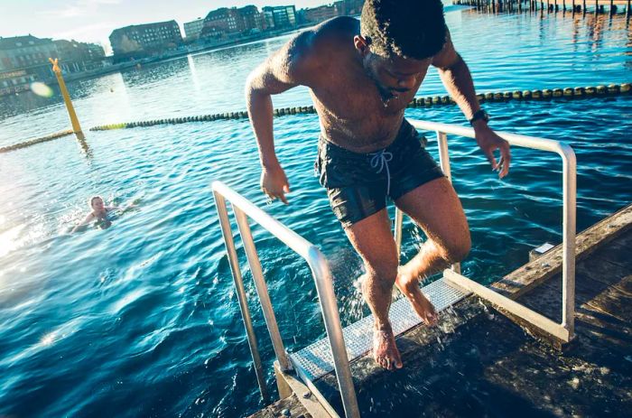 A young man climbs out of the Copenhagen harbor after a refreshing swim.