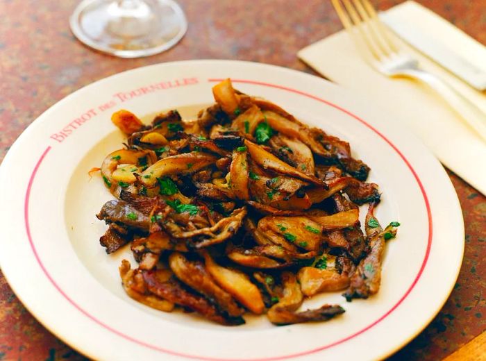 A dish of sautéed oyster mushrooms, complemented by white wine.