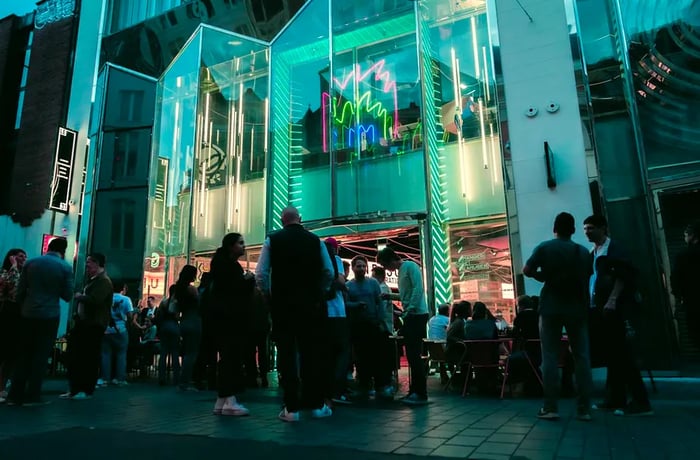 Patrons gather outside a food hall in the evening.