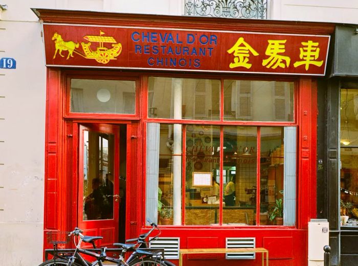 A striking red facade of the restaurant featuring the name Cheval d’Or.