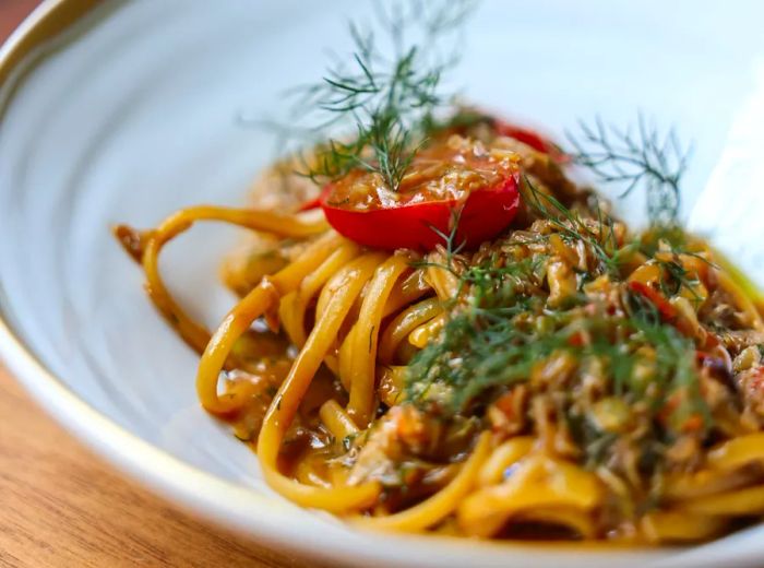 Pasta garnished with tomatoes and fresh herbs.