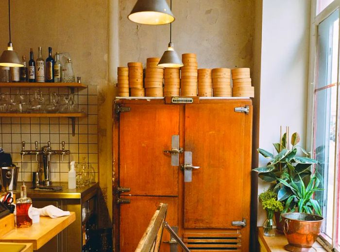 Inside the restaurant, an old wooden fridge is topped with a stack of steamer baskets.