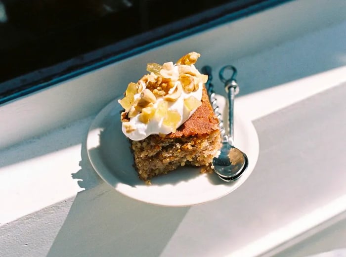 A piece of cake adorned with cream and nuts.