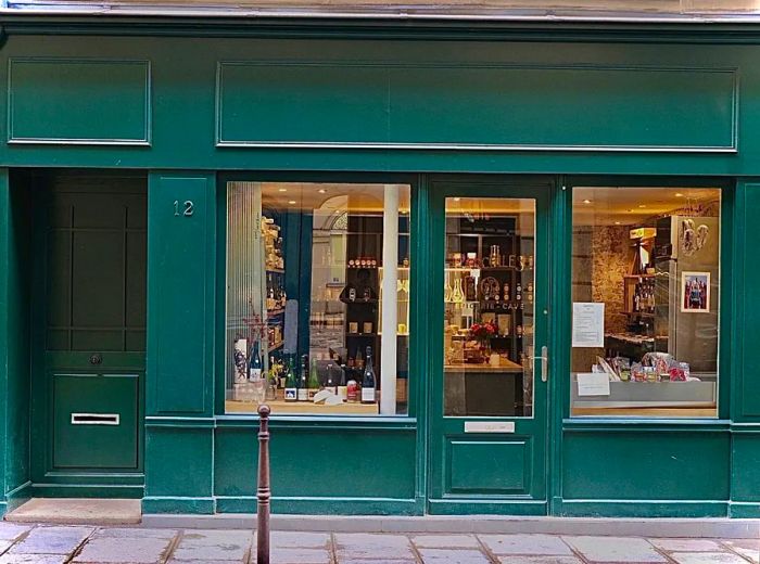 A vibrant green restaurant facade with expansive windows showcasing rows of bottles inside.