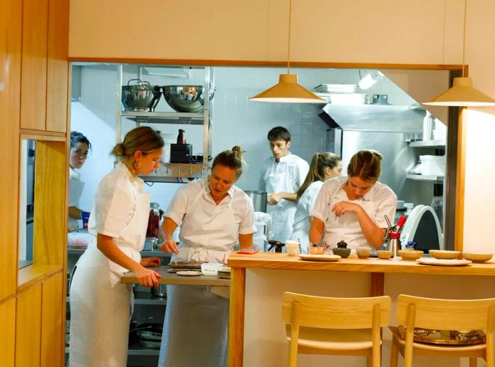 Chefs diligently preparing dishes in an open kitchen adorned with light wood.