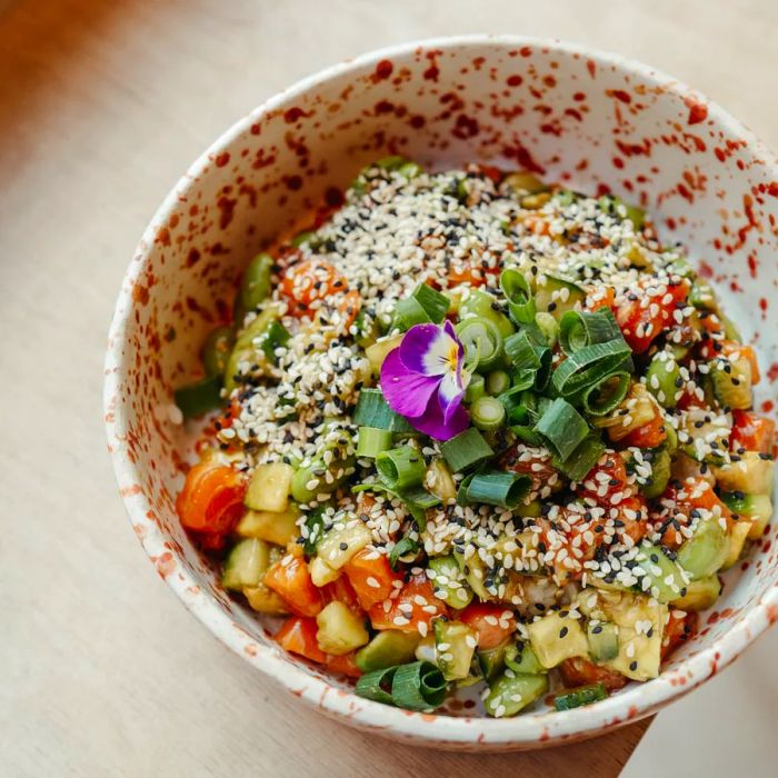 A vibrant chopped vegetable salad garnished with scallions and sesame seeds.