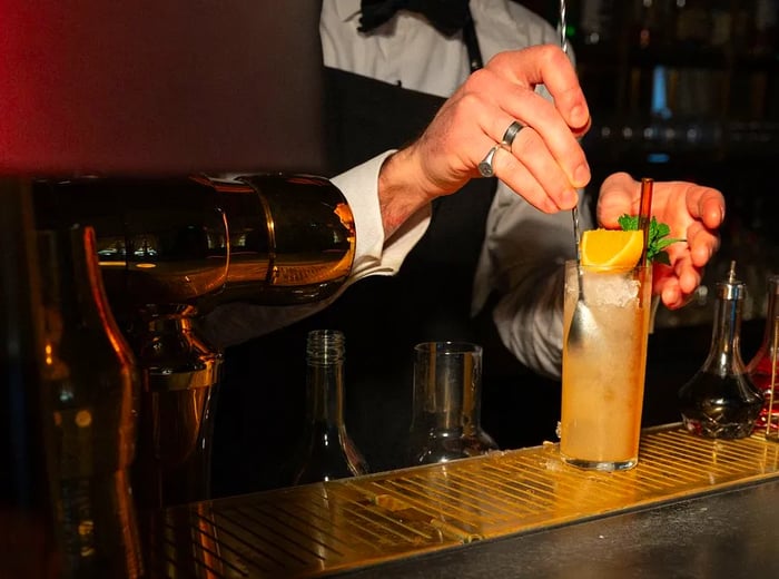 A bartender mixes a highball with precision.