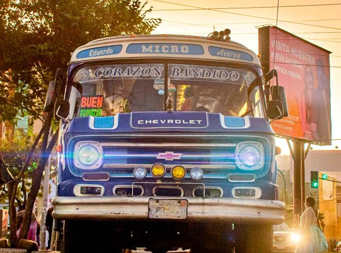 A low-angle view of a small blue bus with a sign reading Buen Provecho displayed on the window.