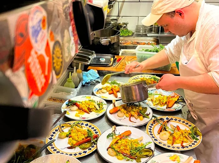 A chef artfully arranges vibrant vegetable dishes.