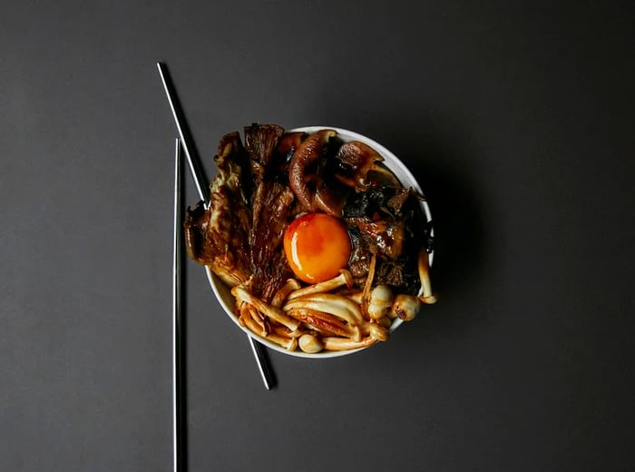 From above, a plate features an assortment of mushrooms adorned with a luscious egg yolk.