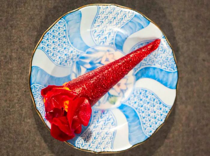 A dish resembling a vibrant red rose elegantly piped into a pastry bag.