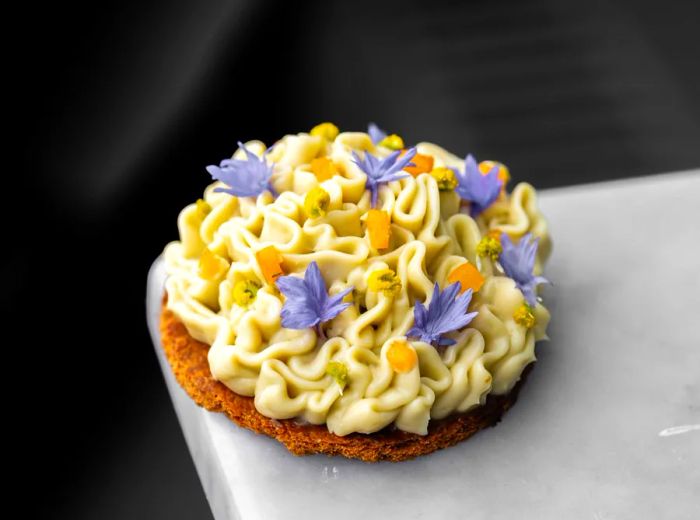 A pastry adorned with a generous swirl of icing and decorated with flowers.