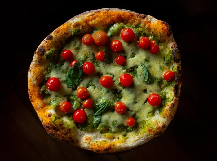 A bird's-eye view of a pizza topped with large round tomatoes.