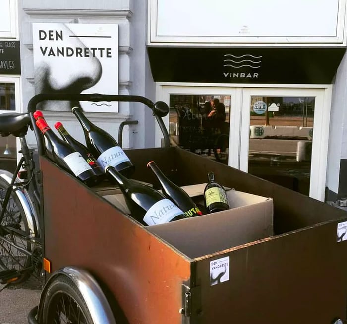 A small pushcart filled with various bottles of wine.