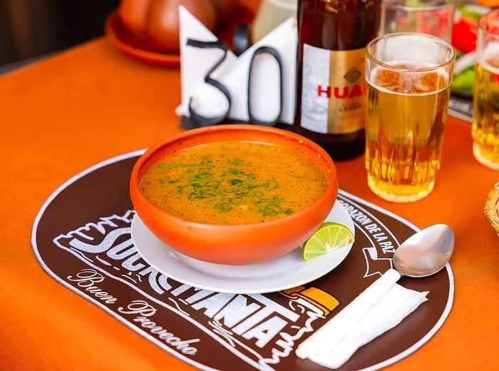 A bowl of soup garnished with chopped herbs.