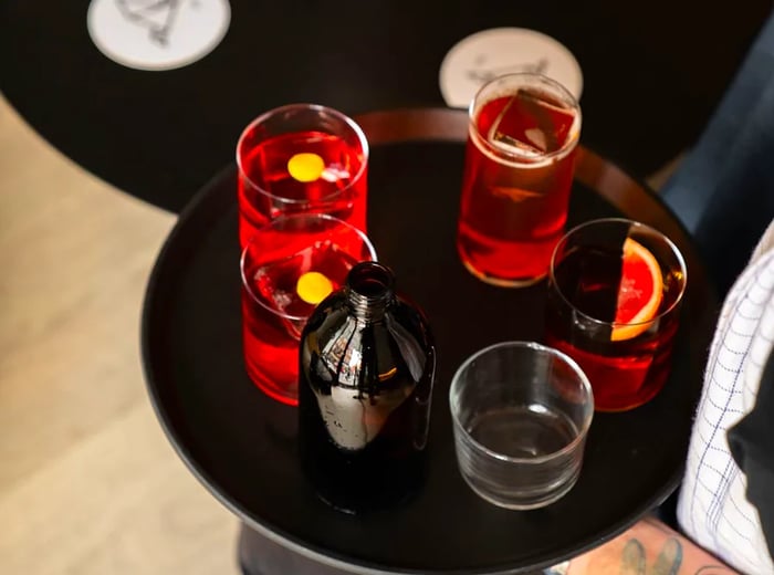 A server presents vibrant red cocktails on a tray.