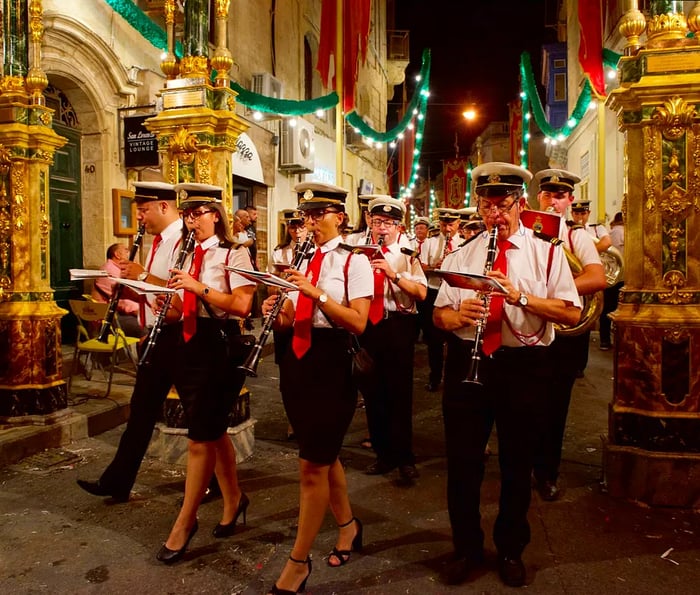 Marching band members parade down a beautifully decorated street during the Feast of Santa Catharina in Zurrieq, Malta.