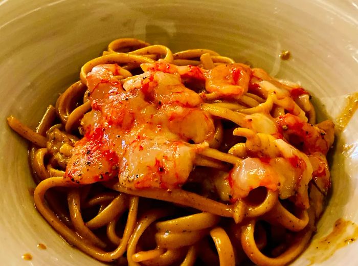 A plate of pasta garnished with shrimp.