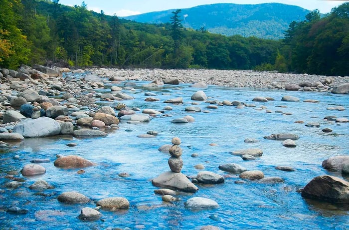 A rock cairn positioned in the middle of a river.