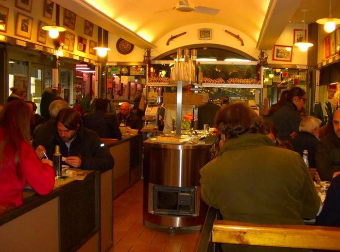 A bustling restaurant interior with a central salad bar, illuminated by strip lighting beneath a domed ceiling, adorned with various pictures and decorations on the walls.