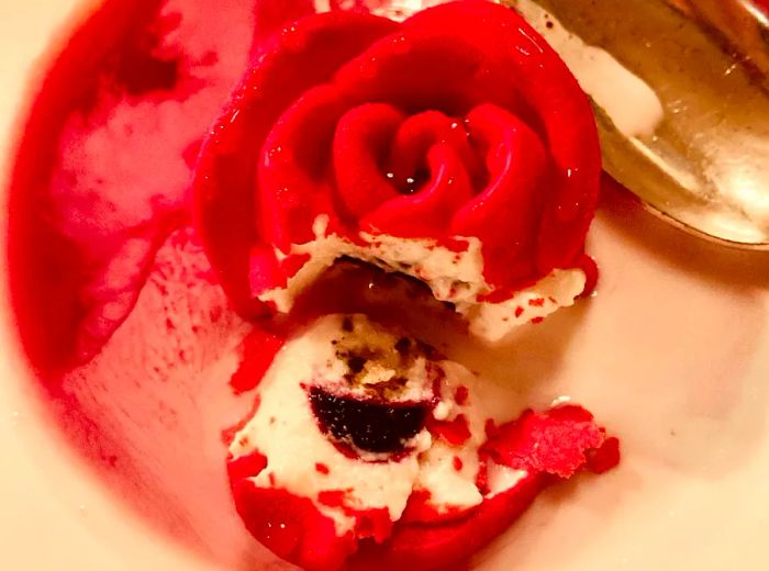 A rose-shaped dessert with a portion cut away to reveal a fruity filling inside.