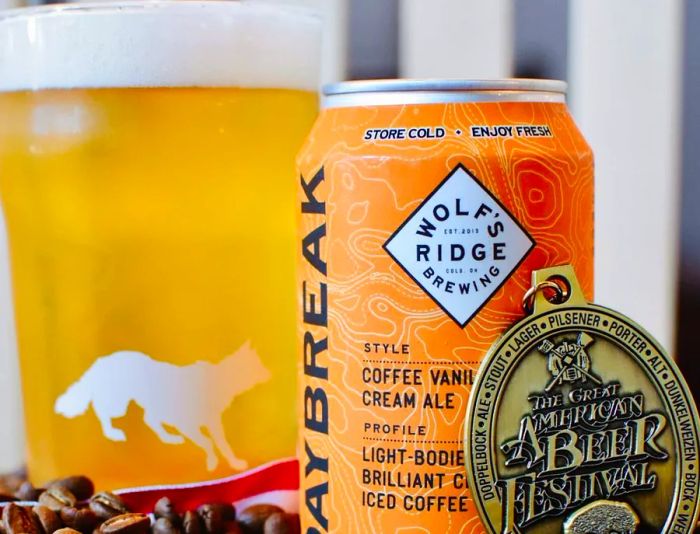 A beer can proudly displayed with a competition medal beside it, along with a tall glass of refreshing light beer.