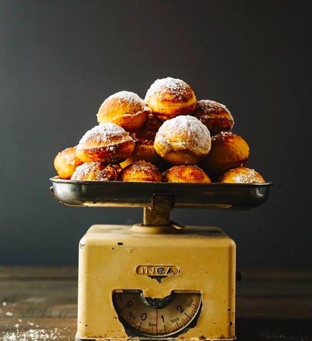 A vintage scale overflowing with sugar-dusted pastry balls.