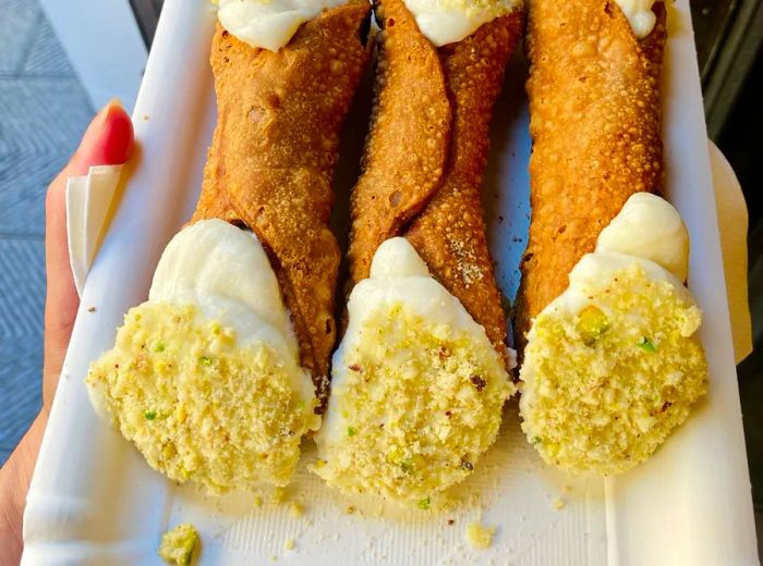 A trio of cannoli elegantly arranged on a decorative disposable plate.