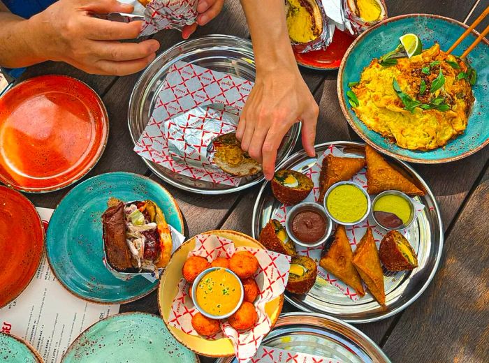 A hand reaches for an array of enticing Bengali dishes.