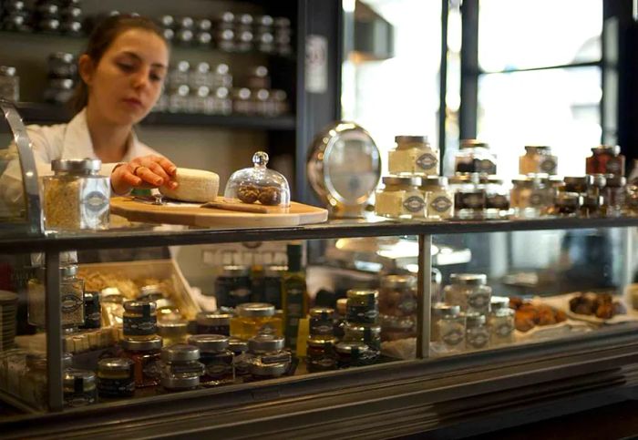 A staff member carefully arranges delicious food items in a glass display case.