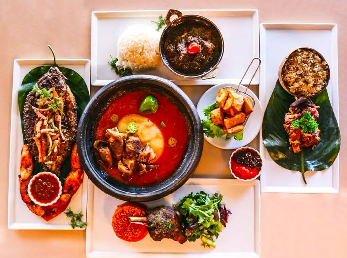 An overhead view showcasing a variety of dishes, including soup, a whole roasted fish, assorted meats, and stewed greens.