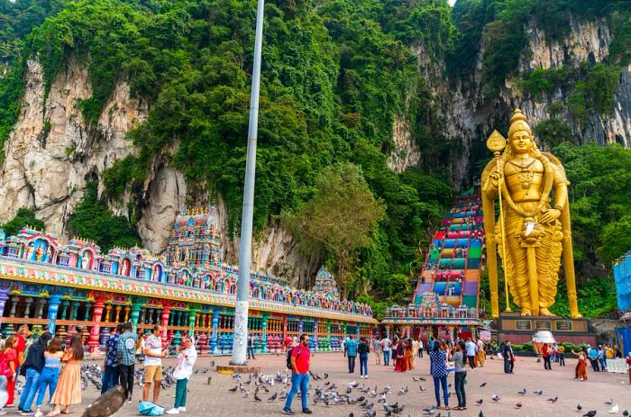 A massive golden statue greets you at the foot of a vibrantly colored staircase that ascends into a network of caves.