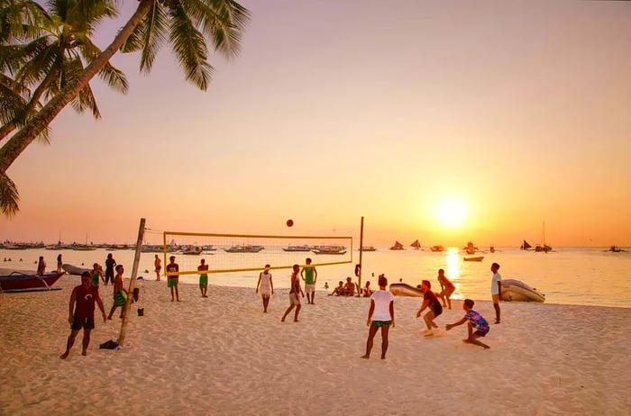 A group enjoys a game of volleyball as the sun sets at White Beach, Boracay Island.