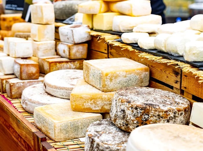 A variety of cheeses beautifully arranged on wooden shelves.